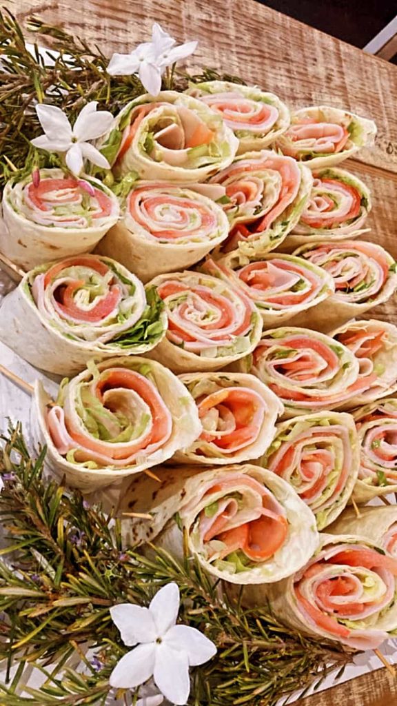 Rollitos de salmón y vegetales frescos presentados con flores para catering en Black & White Cafetería, El Puerto de Santa María