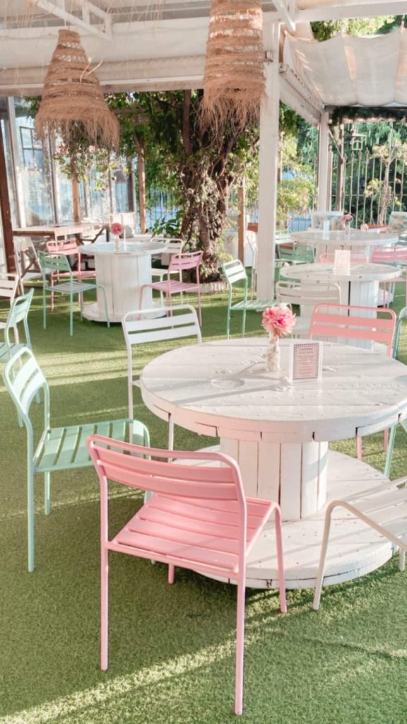 Terraza exterior con mesas redondas, sillas de colores y decoración floral en Black & White Cafetería, El Puerto de Santa María