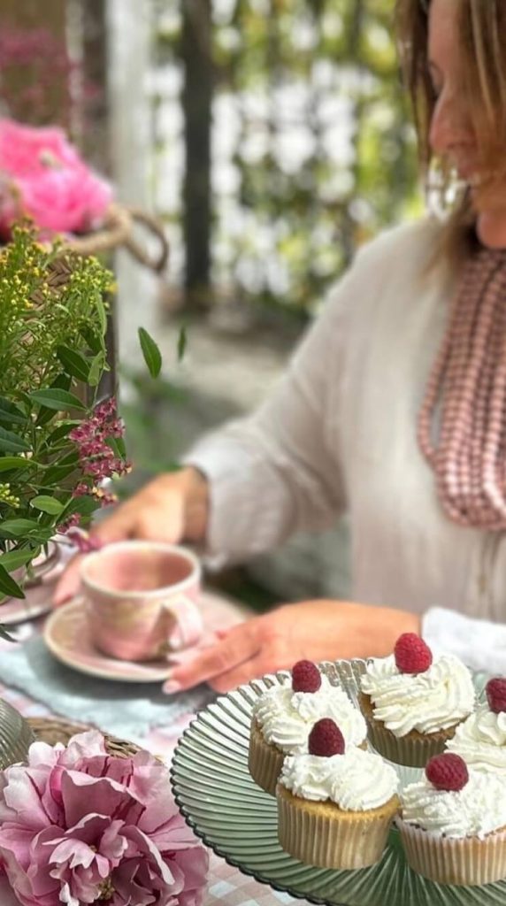 Monika Vera tomando té en una mesa decorada con cupcakes y flores – El Puerto de Santa María